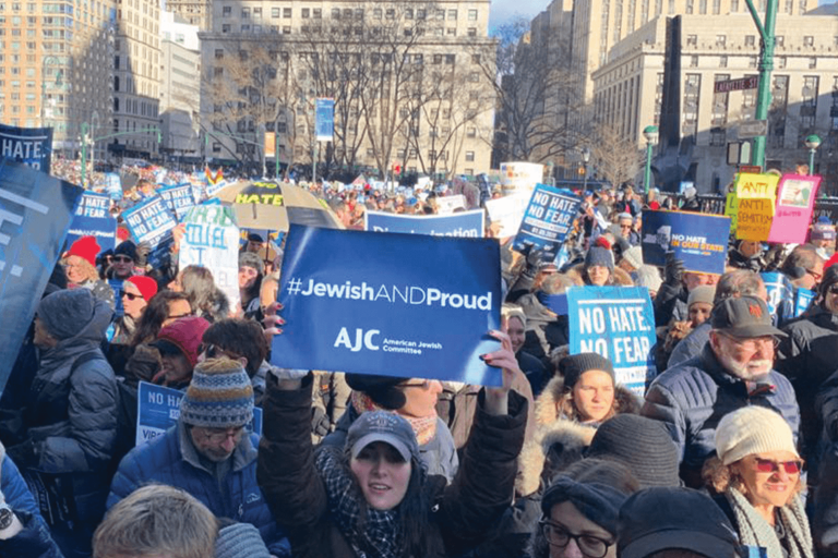 No Hate. No Fear. march in New York - Person holding up a #JewishANDProud - AJC-American Jewish Committee sign