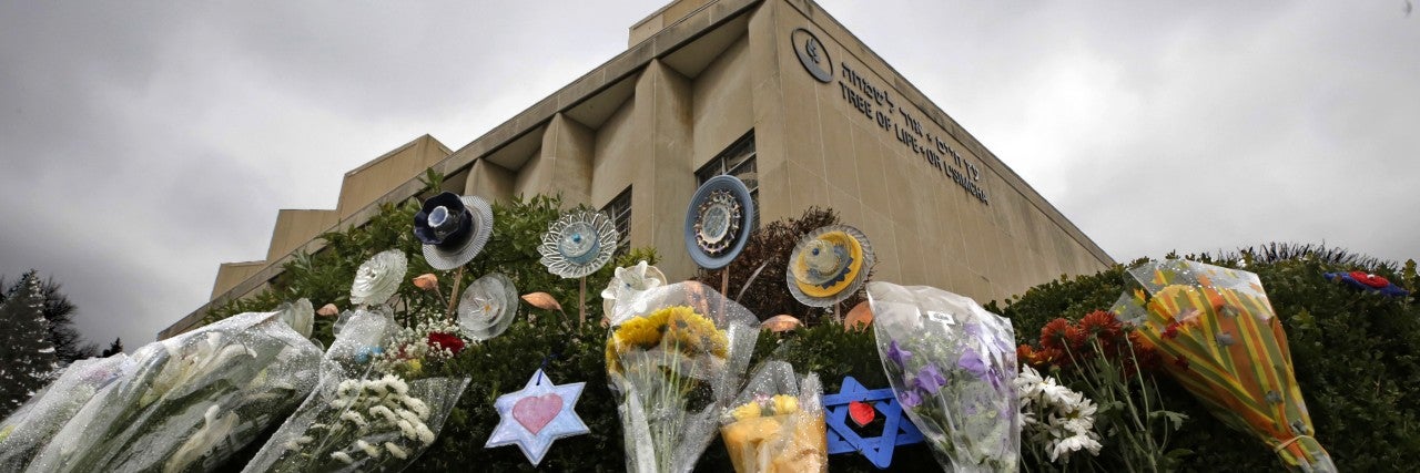 makeshift memorial of flowers, jewish magen david star, rests on bushes outside the Tree of Life Synagogue in Pittsburgh