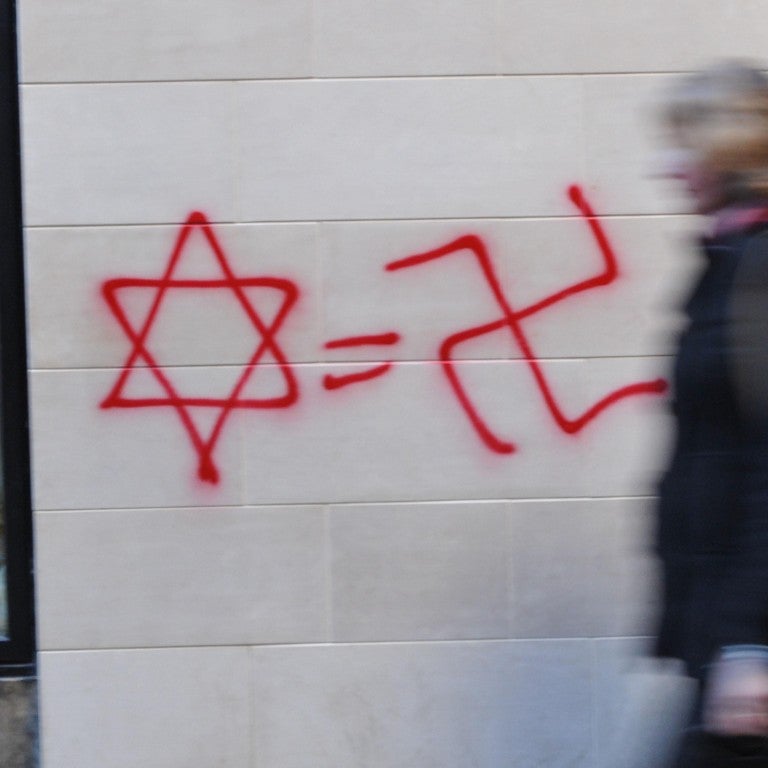 Photo of a star of david and a swatstika on a wall