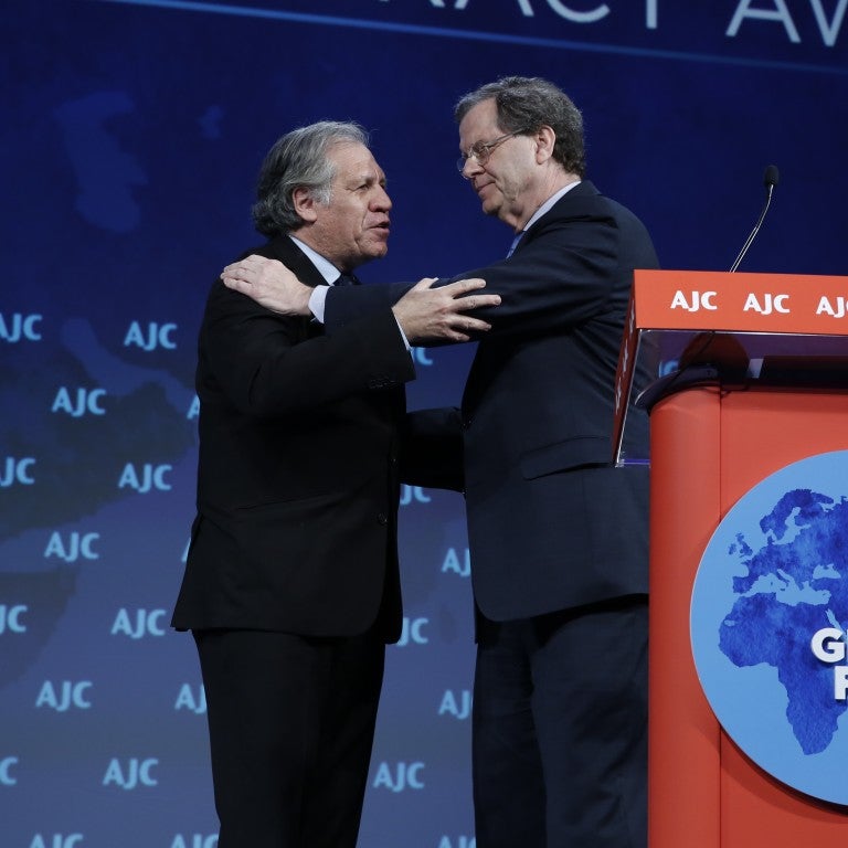 David Harris and Luis Almagro embracing on the AJC Global Forum stage