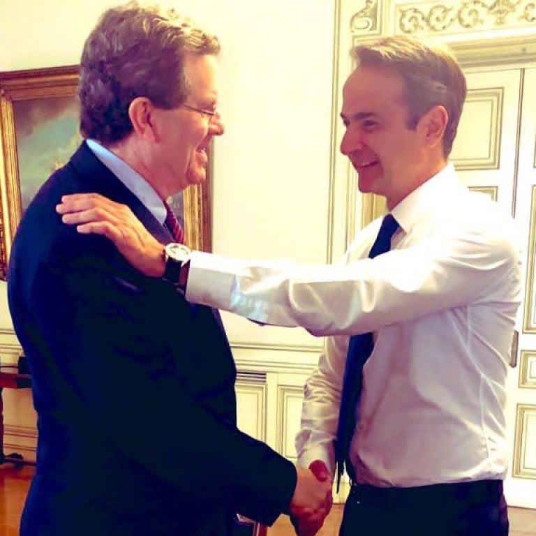 David Harris and PM Kyriakos Mitsotakis embracing