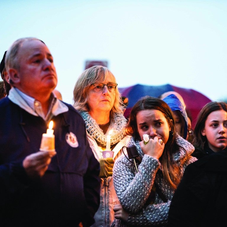 people standing holding candles crying in the daylight in pittsburgh pennsylvania