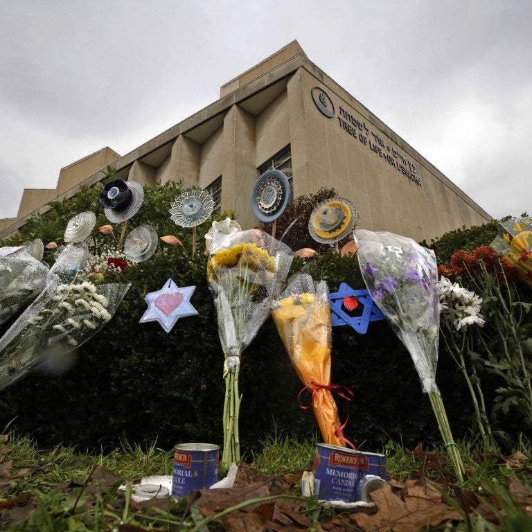 makeshift memorial of flowers, jewish magen david star, rests on bushes outside the Tree of Life Synagogue in Pittsburgh
