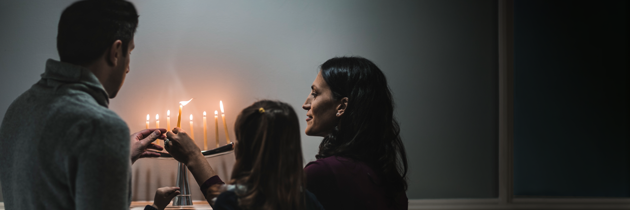 Jewish family lighting candles
