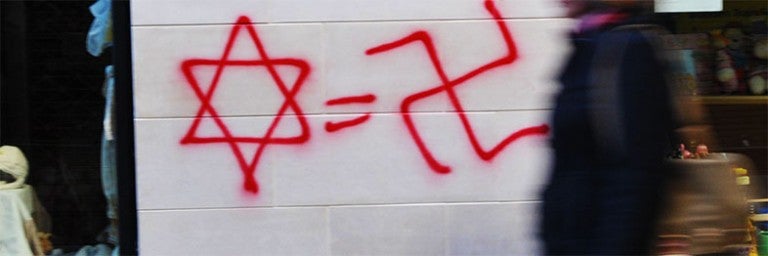 Photo of a Star of David, an equal sign, and a Swastika graffiti-ed on a wall