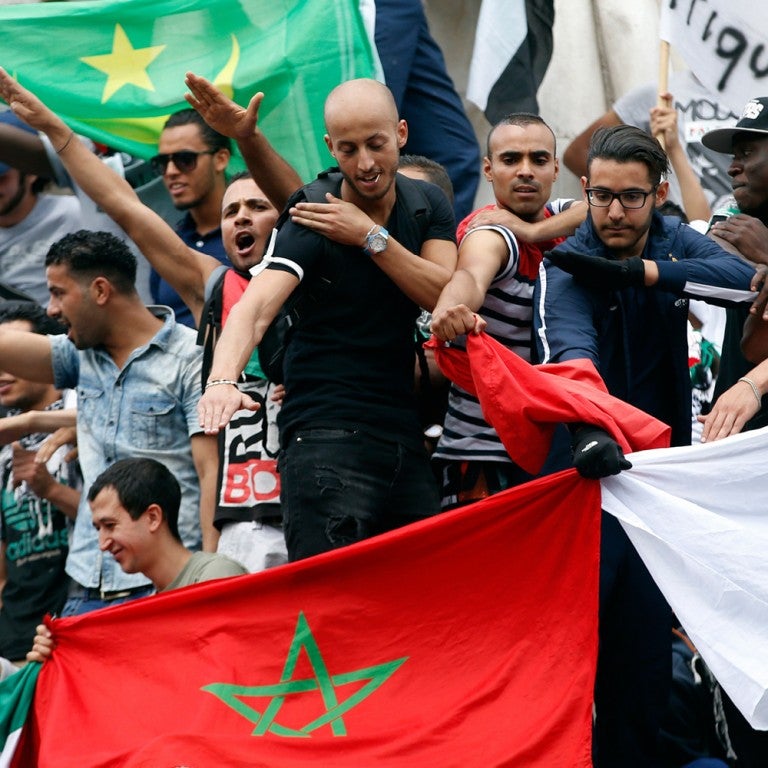 Photo of protesters in Paris, France holding the Algerian flag and doing the "quenelle" 