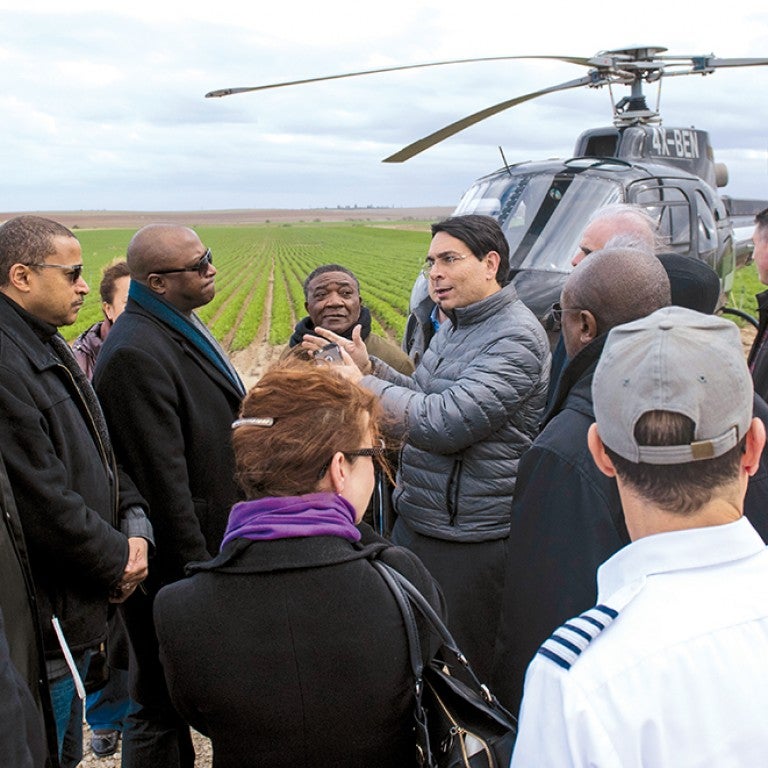 Photo of Danny Danon speaking to an AJC delegation in front of a helicopter