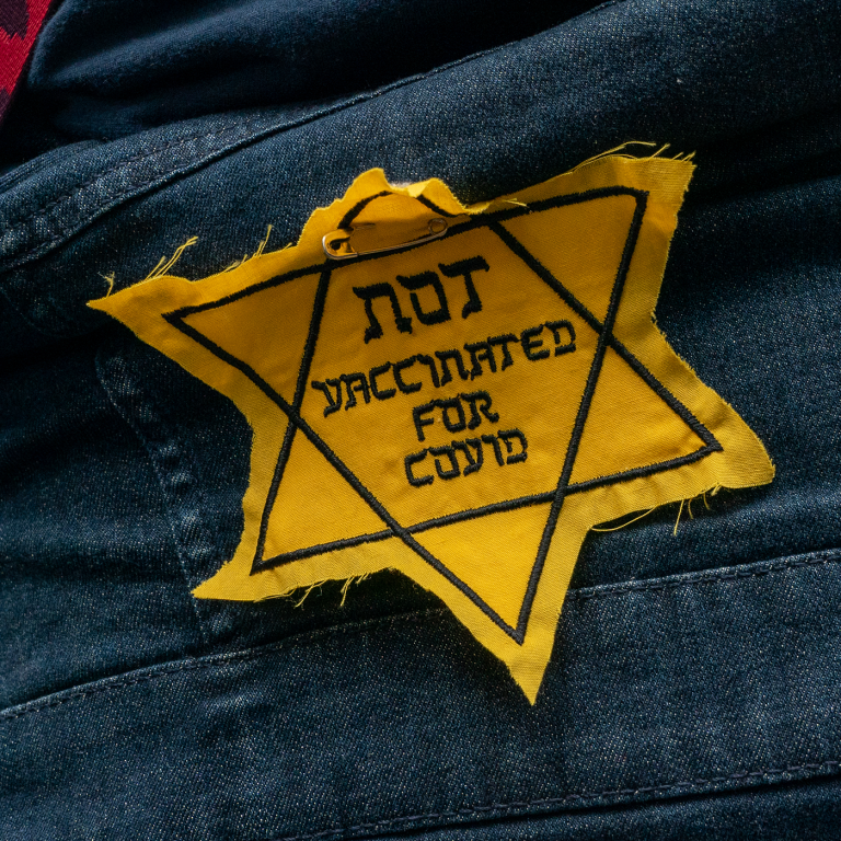 Photo of a yellow star of David patch with the words: "Not vaccinate for Covid" 