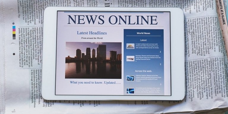 iPad saying "News Online" with a newspaper behind