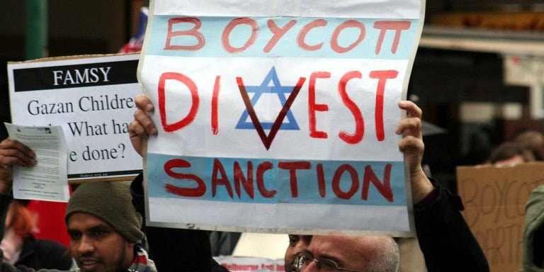Protestor holding a boycott, divest, and sanction (BDS) sign