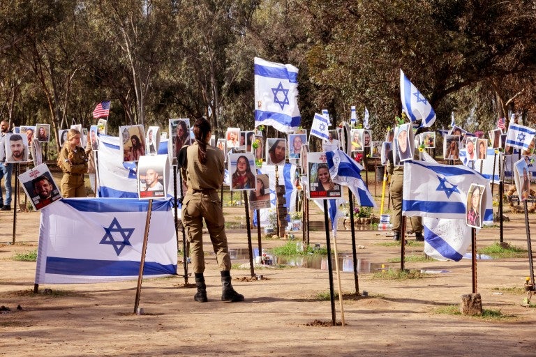  Israeli soldiers walk among portraits of people taken captive or killed by Hamas militants during the Supernova music festival on October 7, during a visit at the site where the deadly incident took place near Kibbutz Reim in southern Israel, on January 11, 2024, amid continuing battles between Israel and Hamas in Gaza. 