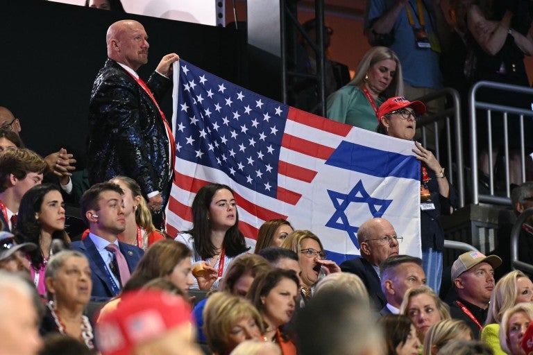 Attendees hold a flag made from the US and Israel flag during the third day of the 2024 Republican National Convention at the Fiserv Forum in Milwaukee, Wisconsin, on July 17, 2024. Days after he survived an assassination attempt Donald Trump won formal nomination as the Republican presidential candidate and picked Ohio US Senator J.D. Vance for running mate. 