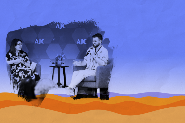 Photo of Adiel Cohen and Manya Brachear Pashman, both smiling and sitting in armchairs with a small endtable in the middle, on a stage in front of a step and repeat with AJC lettering, paintbrush effect around the photo, laid over a graphic representation of the desert