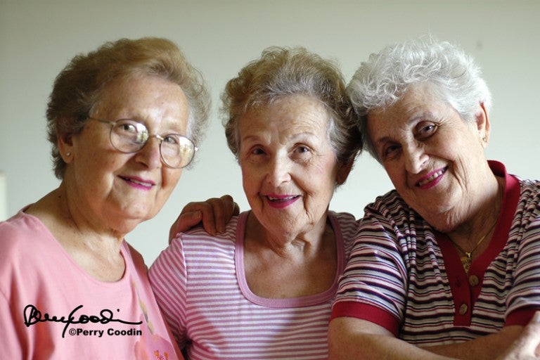 Three older women smiling and posing together. 