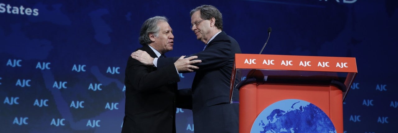David Harris and Luis Almagro embracing on the AJC Global Forum stage
