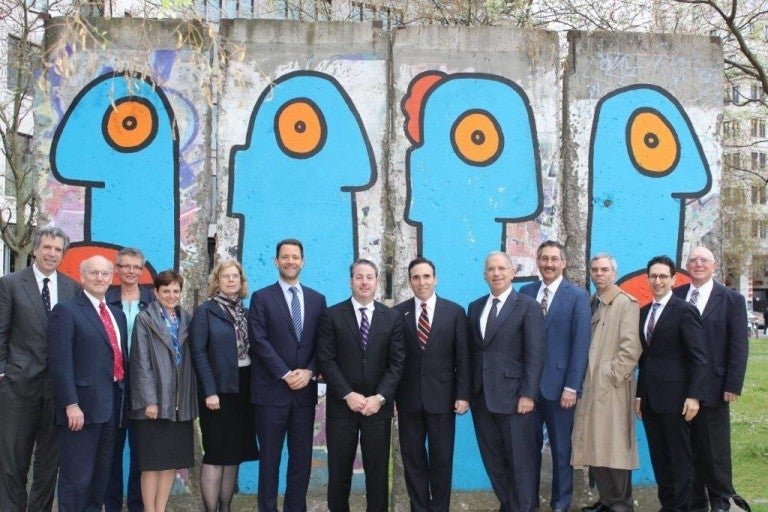 Photo of individuals on AJC-Adenauer Leadership Exchange Program standing in front of the Faces with Big Lips mural on a section of the Berlin Wall