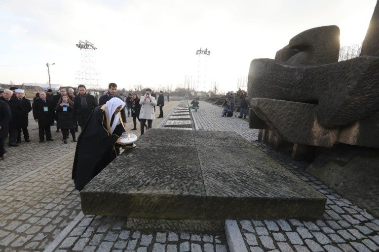 Dr. Al-Issa of the Muslim World League placing a memorial candle at the monument honoring the more than 1.1 million people murdered at the Nazi camp.