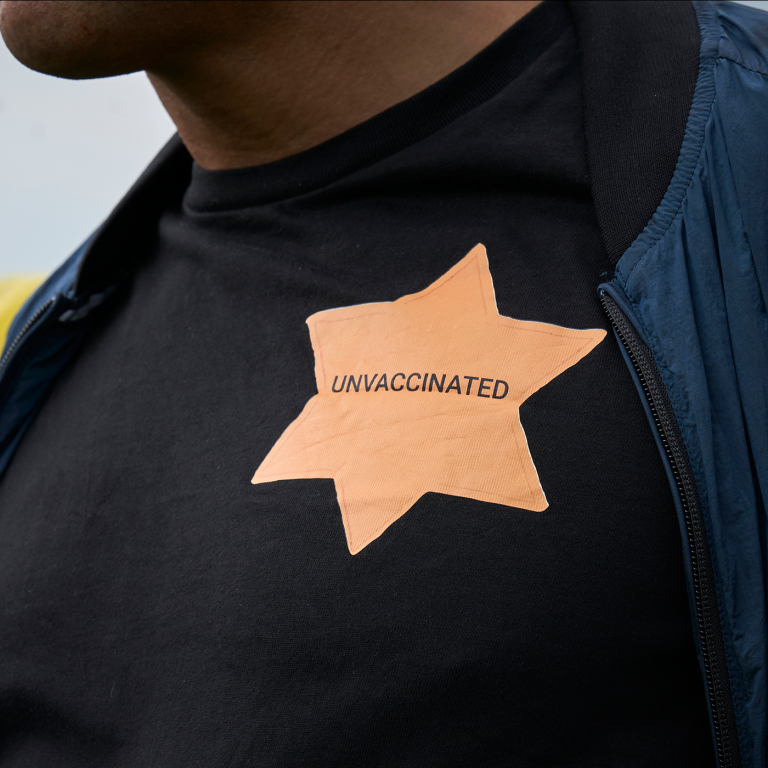 Photo of a man with a yellow Star of David saying "unvaccinated"