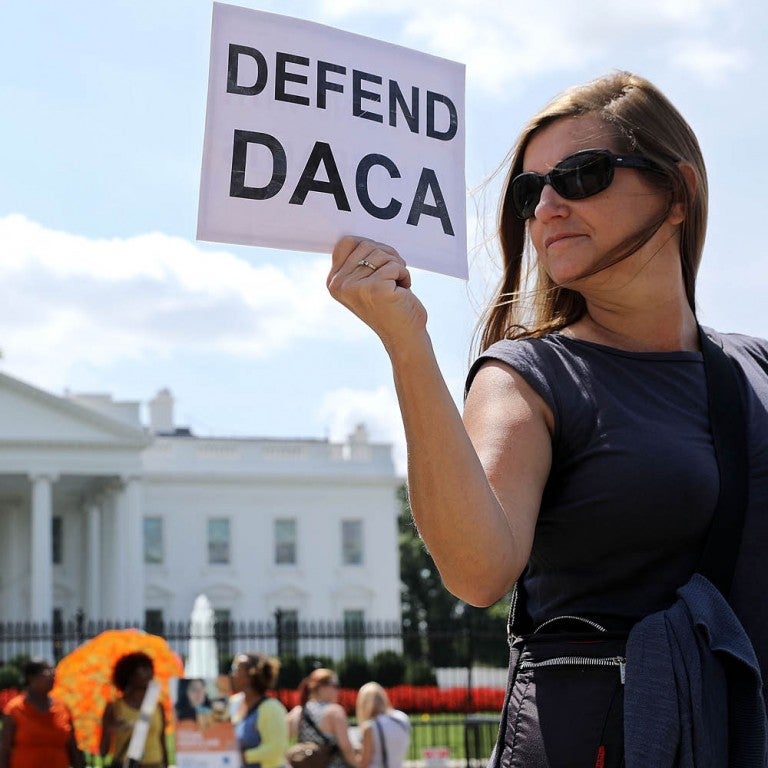 Woman holding a Defend DACA sign infront of the White House